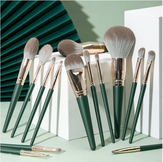 Set of makeup brushes with green handles and gold accents on a light green background